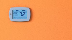 Programmable Thermostat On An Orange Wall
